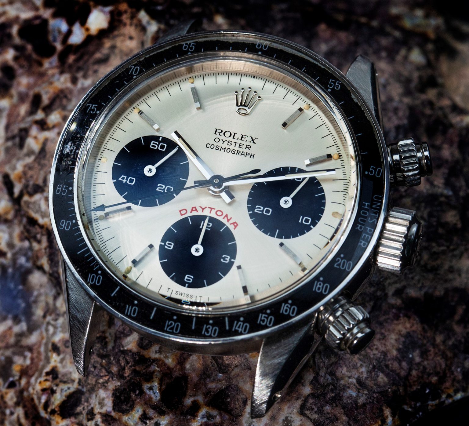 Vintage chronograph watch with black bezel on a dark stone surface
